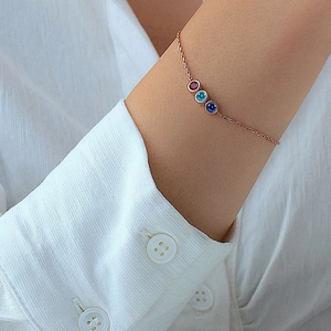 Close-up of a rose gold bracelet with three inlaid rhinestones on a model wrist