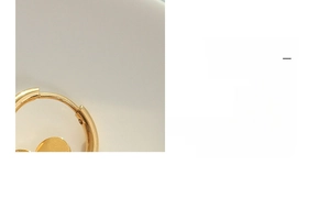 Detailed close-up of a gold-plated titanium steel hoop earring with circular disc pendant