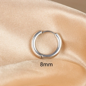 Detailed macro shot of 8mm silver polished stainless steel hoop earring on silk