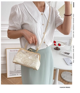 Close-up of beige jacquard evening bag with floral embroidery and gold chain strap