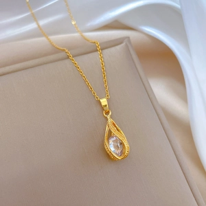 Detailed shot of golden water drop pendant with sparkling crystal on white silk background