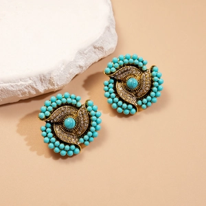 Retro turquoise flower stud earrings with gold metal and crystals on a stone pedestal