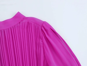 Dettaglio dell'elegante collo alto a pieghe e della manica a spacco su un abito di chiffon rosa