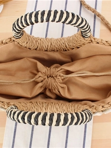 Minimalist straw woven handbag with shell detail and drawstring closure shown from above