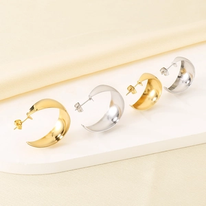 Detailed view of C-shaped stainless steel earrings in gold and silver with mirror finish