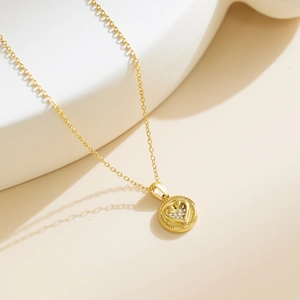 Elegant gold pendant necklace with heart-shaped diamond inlay on a geometric display