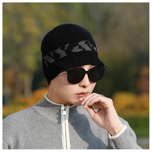 Close-up of black knitted beanie featuring grey NY letter pattern on outdoor male model