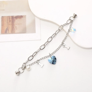 Detailed view of silver double-layered chain bracelet with blue crystal heart charm