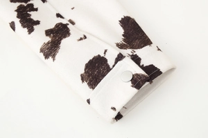 Detail of black and white cow print jacket cuff with a silver metal snap button
