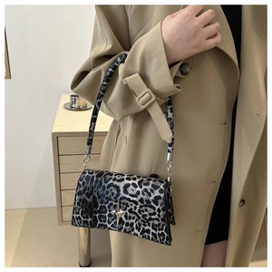 Dettaglio borsa leopardata grigia con fibbia a stella argentata su trench color kaki