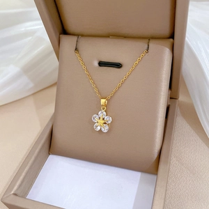 Close-up of gold star flower pendant with white zircon in a beige jewelry box