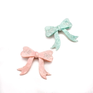 Pink and mint green acetate bow hair clips with marble texture and sparkling rhinestones