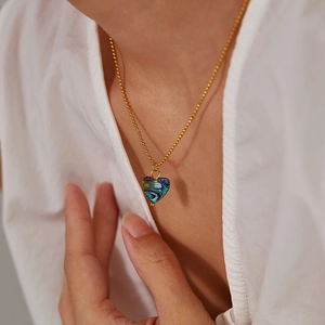 Detail of heart pendant necklace with iridescent abalone shell on a gold ball chain
