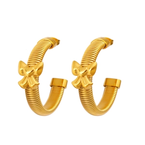 Détail de boucles d'oreilles créoles dorées à texture spirale et breloques nœud et cœur