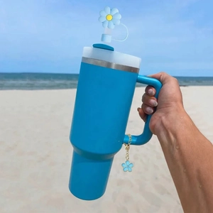 Close-up of blue tumbler with handle featuring a matching flower straw cover and charm