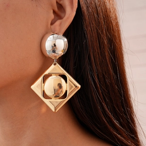 Close-up of geometric gold and silver metal earrings with mixed shapes on a model