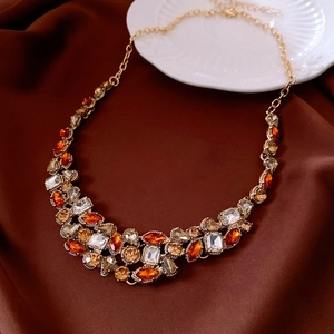 Detail view of a vintage crystal teardrop necklace on brown silk with golden accents