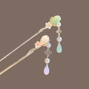 Chinese style flower hairpin with jade-like petals and golden tassels on warm background
