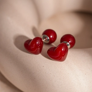Gros plan de boucles d'oreilles cœur en résine rouge sur un support décoratif beige