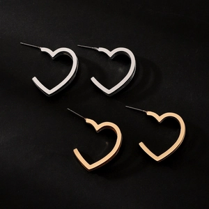 Close-up of heart-shaped hollow earrings in polished gold and silver metallic finishes