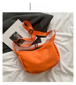 Detailed top view of an orange nylon crescent bag with black zippers and adjustable strap