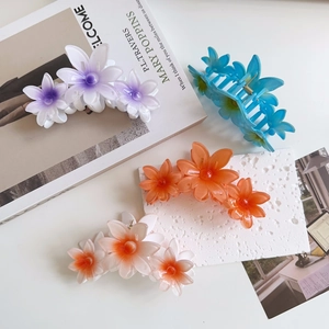 Detail of four candy-colored flower hair claws in translucent resin on a white desk