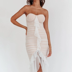 Detail of tiered mesh ruffles on a beige strapless bodycon midi dress