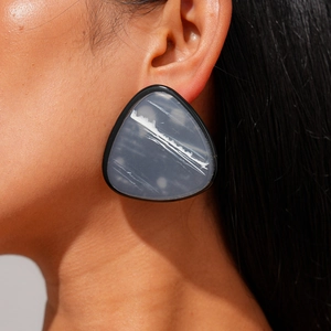 Detailed close-up of large geometric triangle resin earrings with grey marble pattern