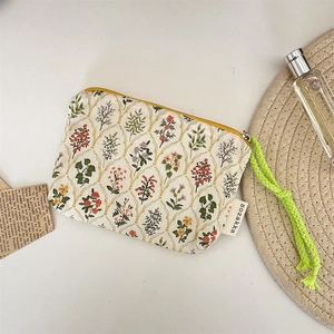 Detail of floral zipper pouch with green braided rope handle and vintage pattern