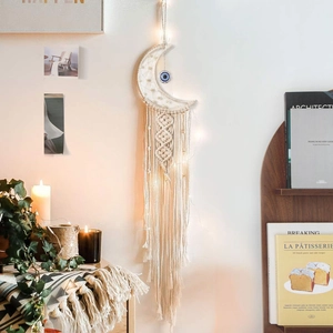Detail of moon-shaped macrame wall hanging with evil eye bead and LED string lights