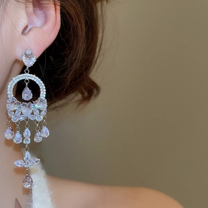 Macro detail of large silver tassel earrings with zircons on model showing elegant drape