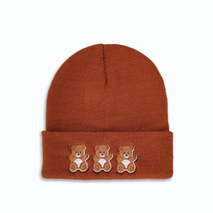Close-up of three brown cartoon bear embroidery on a dark brown knit beanie hat