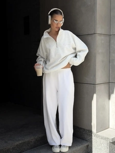 Detail of light gray half-zip hoodie with cursive embroidery and white wide-leg sweatpants