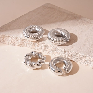 Close-up of four silver metal ear cuffs featuring smooth, twisted, and ribbed textures