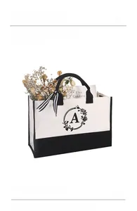 Detailansicht der weißen Canvas-Tasche mit schwarzem A-Aufdruck und gestreifter Schleife