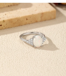 Macro shot of silver ring featuring oval opal center stone and accent diamonds detail