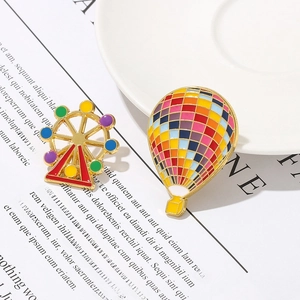 Detailed shot of colorful enamel Ferris wheel and hot air balloon brooches with gold plating