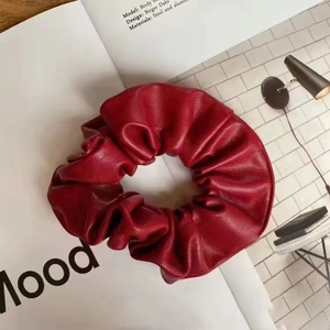 Close-up of deep red PU leather scrunchie with lychee texture on a lifestyle magazine
