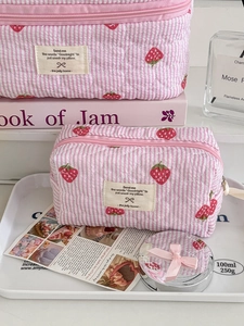 Detail of pink quilted strawberry pouch with striped pattern and secure zipper closure