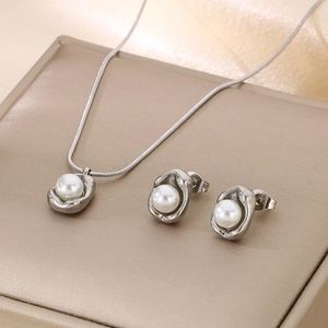 Detail shot of silver necklace and earrings with white pearls on a beige jewelry box