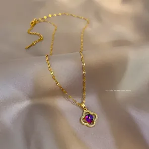 Macro detail of gold clover pendant with crystals and gradient gemstone on satin fabric
