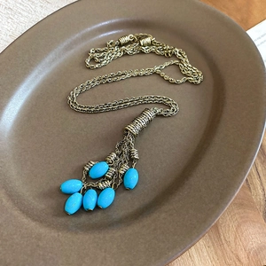 Detail of bohemian necklace with blue stone tassels on a ceramic tray over wood