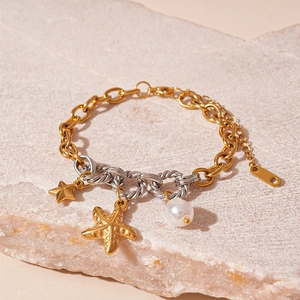 Detail of octopus and starfish ocean charms on a gold mixed metal chain with white pearl