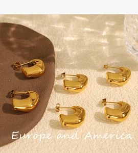 Detailed flat lay of three pairs of geometric gold stainless steel earrings on a beige surface