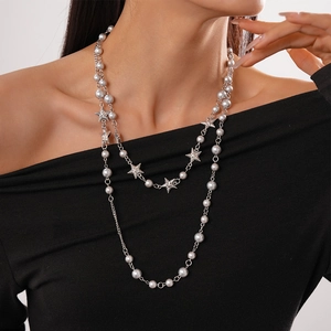 Close-up of a layered pearl and star necklace on a model wearing an off-shoulder dress