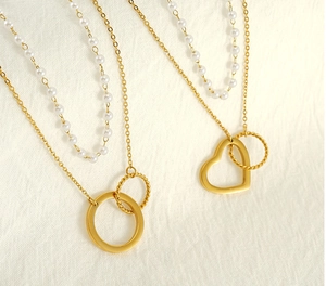 Detail of double-layer necklace with gold heart pendant and elegant white pearls