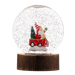 Boule à neige de Noël lumineuse avec Père Noël dans une voiture rouge et socle bronze