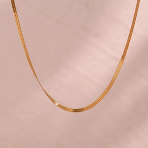 Detail of 2mm 18K gold plated stainless steel flat blade chain necklace on pink surface