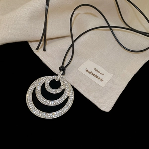 Detail showing crystal-studded triple circle pendant on minimalist black leather cord necklace