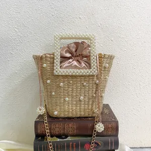 Handmade woven straw bucket bag with pearl embellishments and a satin drawstring liner